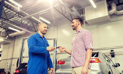 Image showing auto mechanic giving key to man at car shop