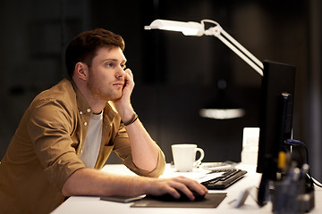 Image showing tired or bored man working late at night office