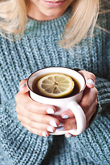 Image showing Female hands holding mug of hot tea with lemon in morning. Young