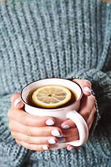 Image showing Female hands holding mug of hot tea with lemon in morning. Young