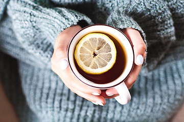 Image showing Female hands holding mug of hot tea with lemon in morning. Young