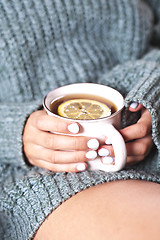 Image showing Female hands holding mug of hot tea with lemon in morning. Young