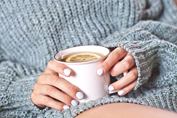 Image showing Female hands holding mug of hot tea with lemon in morning. Young