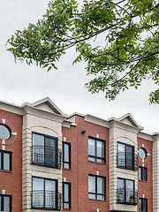 Image showing Green leaves and modern brick building