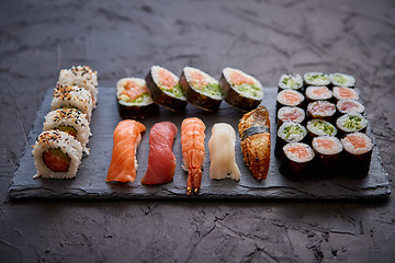 Image showing Sushi rolls set with salmon and tuna fish served on black stone board