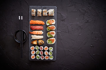 Image showing Sushi rolls set with salmon and tuna fish served on black stone board