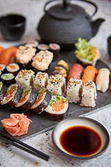 Image showing Assortment of different kinds of sushi rolls placed on black stone board