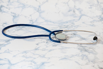 Image showing Medical stethoscope or phonendoscope over light blue background Tablet in the fingers of hand