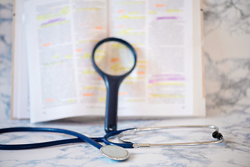 Image showing Stethoscope, magnifier and book Tablet in the fingers of hand