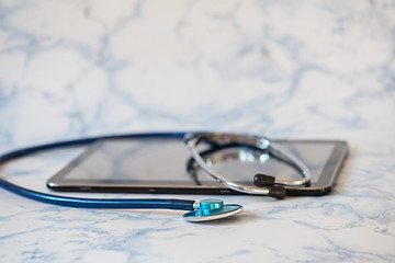 Image showing Stethoscope and notebook Tablet in the fingers of hand