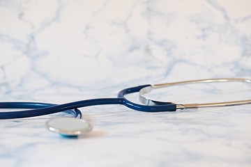 Image showing Medical stethoscope or phonendoscope over light blue background Tablet in the fingers of hand