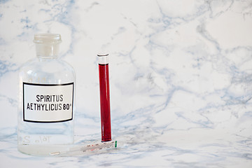 Image showing Ethanol in a bottle and blood analysis Tablet in the fingers of hand