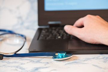 Image showing Stethoscope and notebook Tablet in the fingers of hand