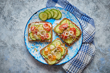 Image showing Plate with toasts with cucomber, tomatoes and crumbled feta and radish sprouts