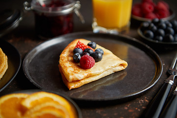 Image showing Tasety homemade pancake on black ceramic plate.