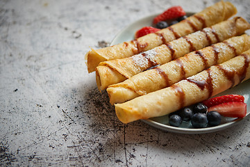 Image showing Plate of delicious crepes roll with fresh fruits and chocolate