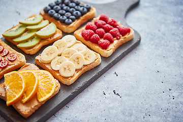 Image showing Wholegrain bread slices with peanut butter and various fruits