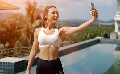 Image showing Cheerful sportswoman taking selfie on poolside