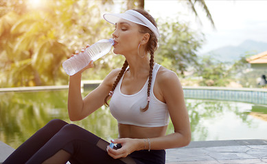 Image showing Sporty female drinking water during workout