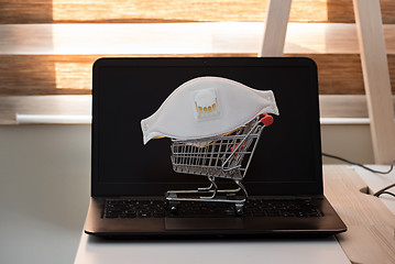 Image showing Conceptual photo with miniature shopping-cart and protecting mask. Safety internet shopping