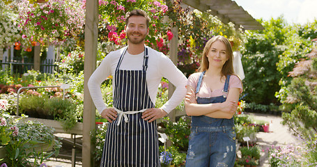 Image showing Outdoors shot of cheerful male and female gardeners looking at camera