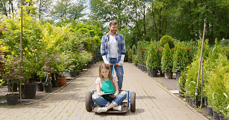 Image showing Woman gardner sitting on wagon in garden and doing paperwork