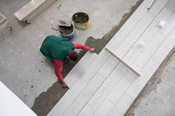 Image showing worker installing the ceramic wood effect tiles on the floor