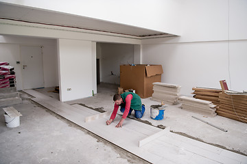 Image showing worker installing the ceramic wood effect tiles on the floor