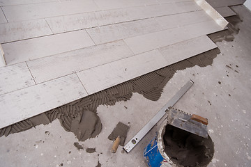 Image showing Ceramic wood effect tiles and tools for tiler on the floor