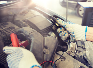 Image showing auto mechanic man with cleats charging battery