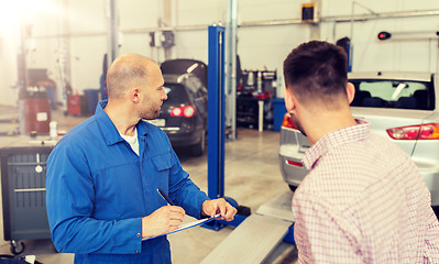 Image showing auto mechanic with clipboard and man at car shop