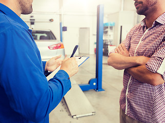 Image showing auto mechanic with clipboard and man at car shop