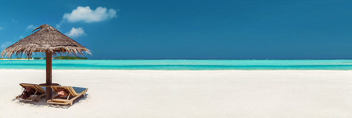 Image showing two sunbeds under palapa on maldives beach