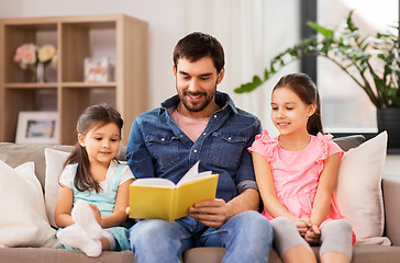 Image showing happy father with daughters reading book at home