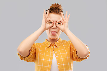 Image showing red haired teenage girl making finger glasses