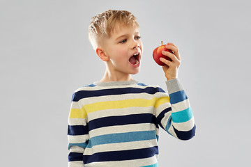 Image showing boy in striped pullover eating red apple