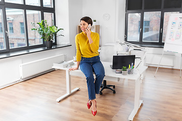 Image showing happy woman and calling on smartphone at office