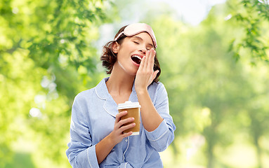 Image showing woman in pajama and eye mask with coffee yawning