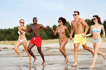 Image showing happy friends running on summer beach