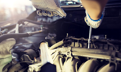 Image showing mechanic man with wrench repairing car at workshop