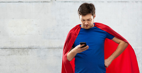 Image showing young man in red superhero cape using smartphone