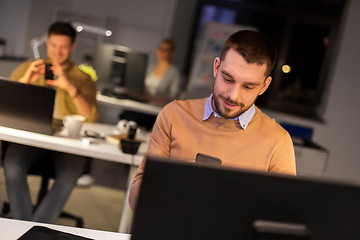 Image showing man with smartphone working late at night office