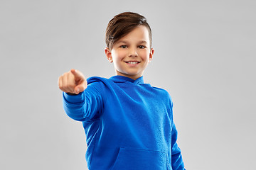 Image showing smiling boy in blue hoodier pointing finger