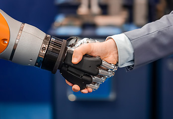 Image showing Hand of a businessman shaking hands with a Android robot.