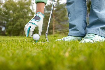 Image showing Hand in glove placing golf ball on tee