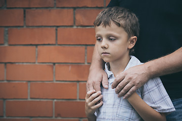 Image showing Portrait of young sad little boy and father standing outdoors at