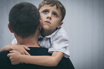 Image showing Portrait of young sad little boy and father standing outdoors at