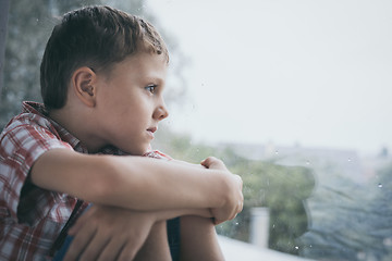 Image showing portrait one sad little boy sitting near a window