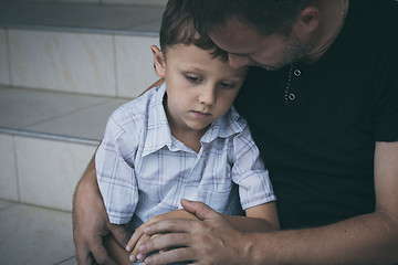 Image showing Portrait of young sad little boy and father sitting outdoors at 