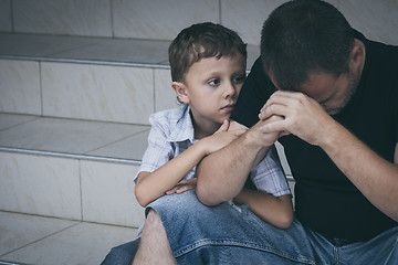 Image showing Portrait of young sad little boy and father sitting outdoors at 